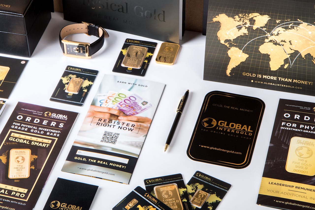 Home Flat lay of promotional materials for gold investment, featuring brochures, cards, and gold bars.